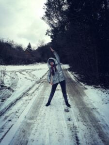 Marta robi ćwiczenie rozciągające bok ciała na zaśnieżonej drodze